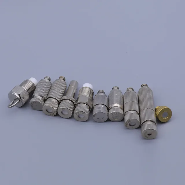 A row of assorted silver and gold metal connectors and adapters on a plain background