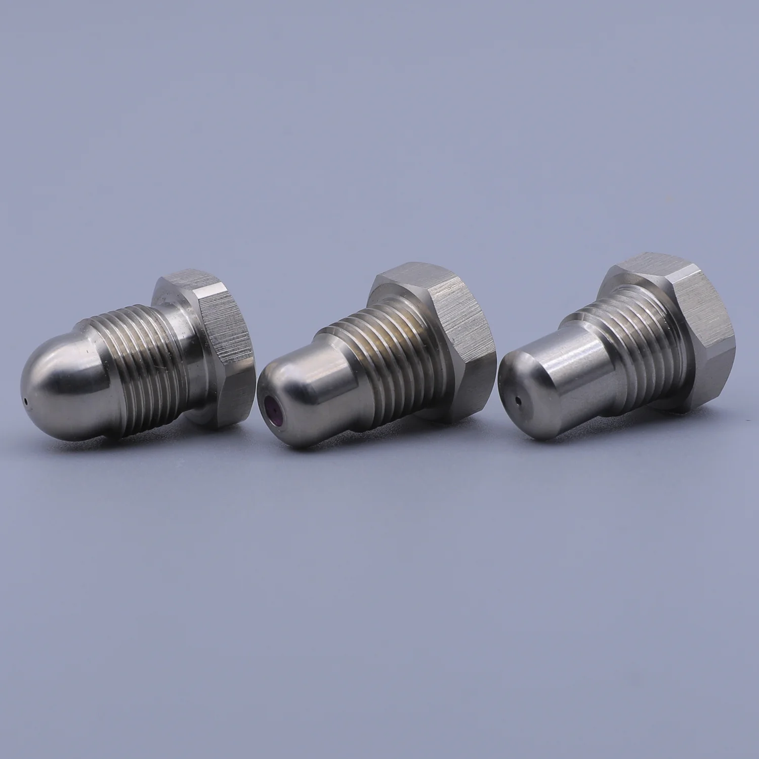 Three stainless steel spray nozzles with hexagonal bases arranged on a light grey background