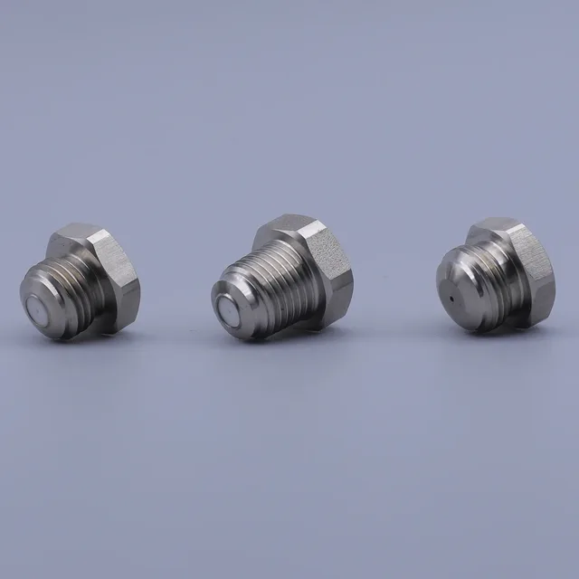 Three stainless steel threaded fittings with hex bases arranged on a plain background
