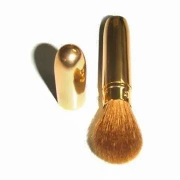 Gold retractable powder brush with soft goat hair shown beside its gold cap