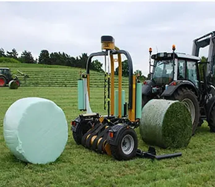 Bale wrapper applying silage film to a round grass bale in the field