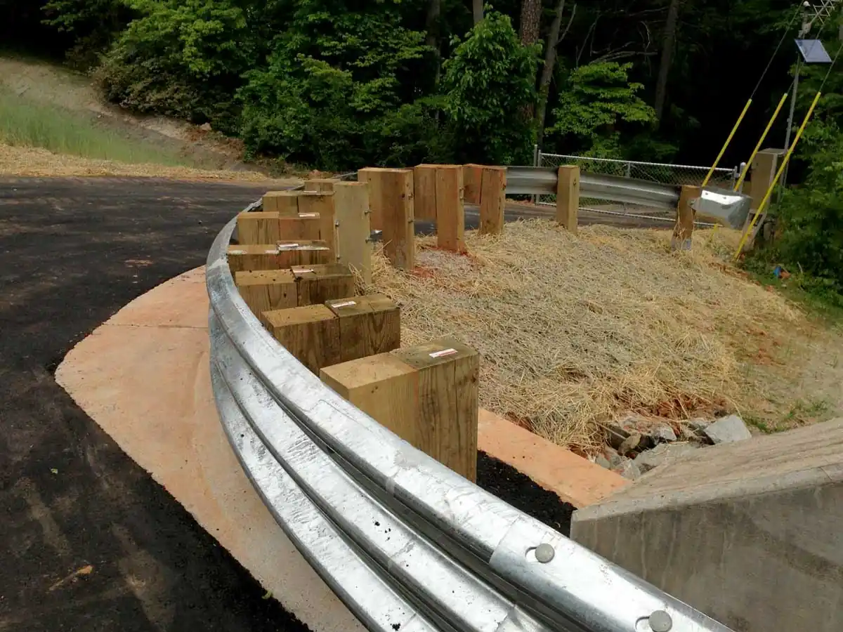 Curved thrie-beam guardrail installed at a highway curve, showing smooth transition