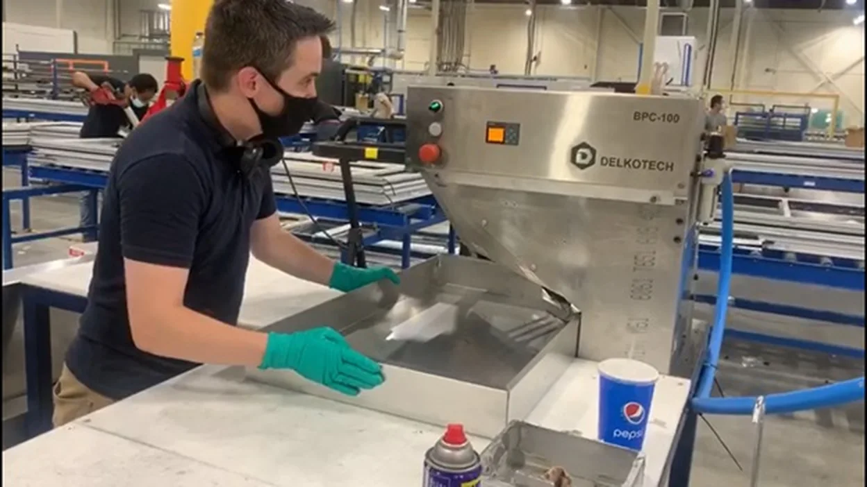 Operator loading a sheet metal panel into a Delkotech RPC-100 clinching press