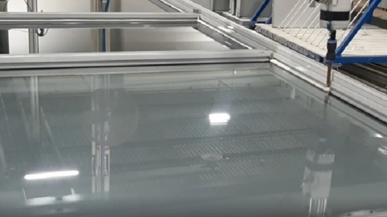 Large glazed panel on the bed of a CNC silicon window machine
