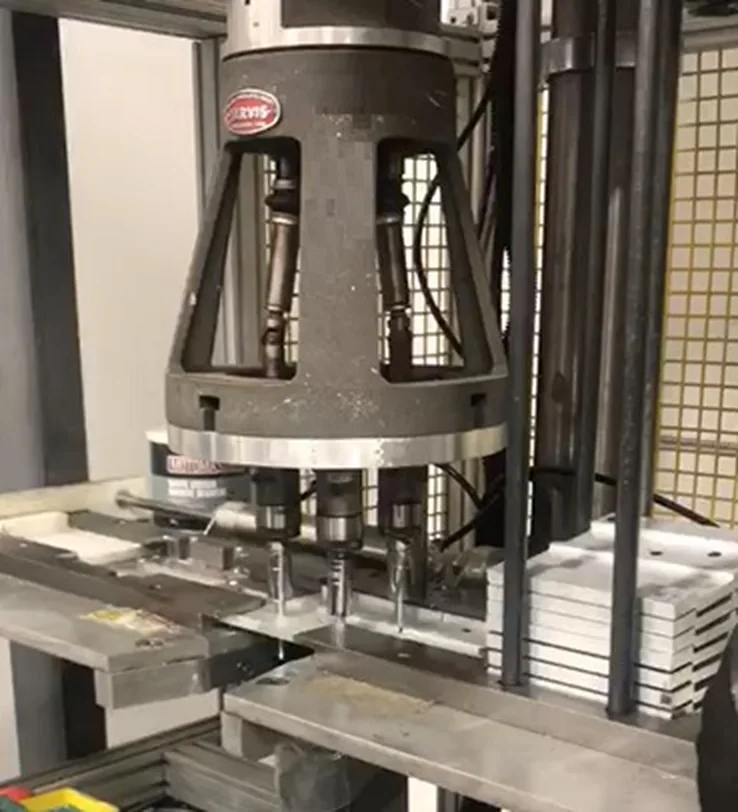 Multi-spindle press head working over a stack of aluminium panels