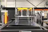 Pick and place gantry raised above the laser cutting bed between cycles