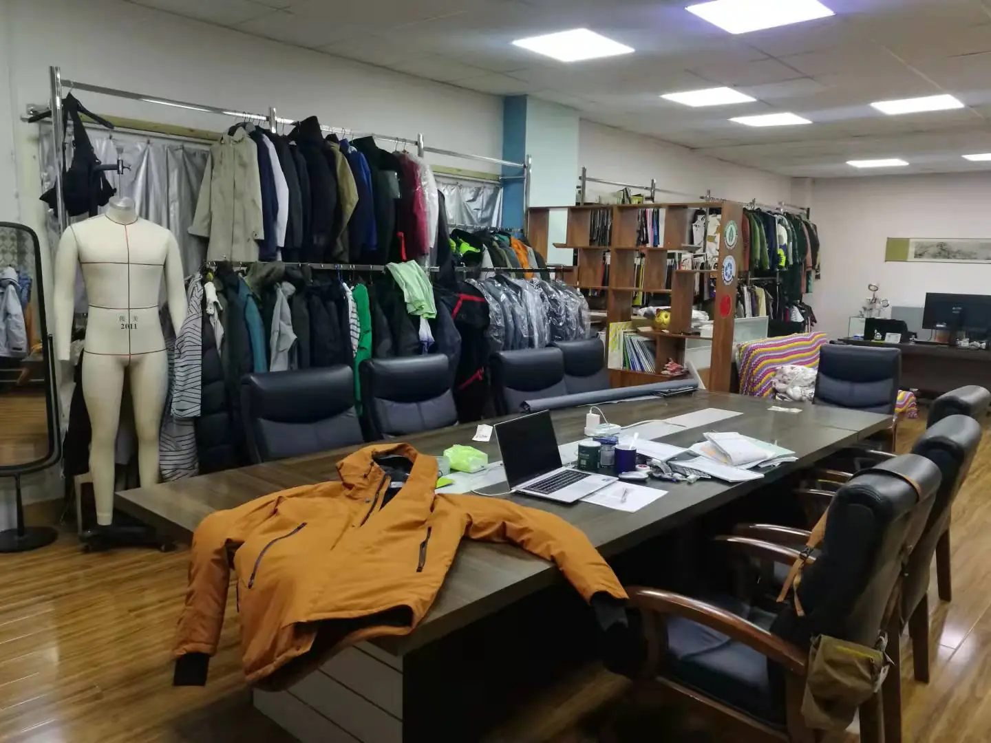 Y&D sample room in Dalian with outerwear rails, a fitting form and an orange shell jacket on the meeting table