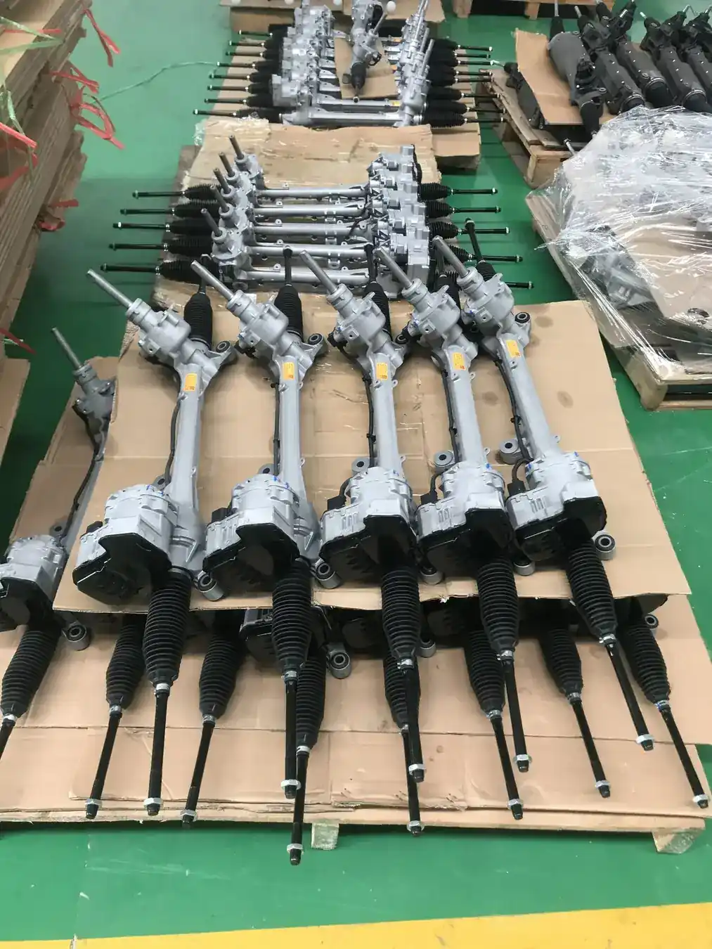 Batch of assembled steering rack units resting on a pallet in the assembly area