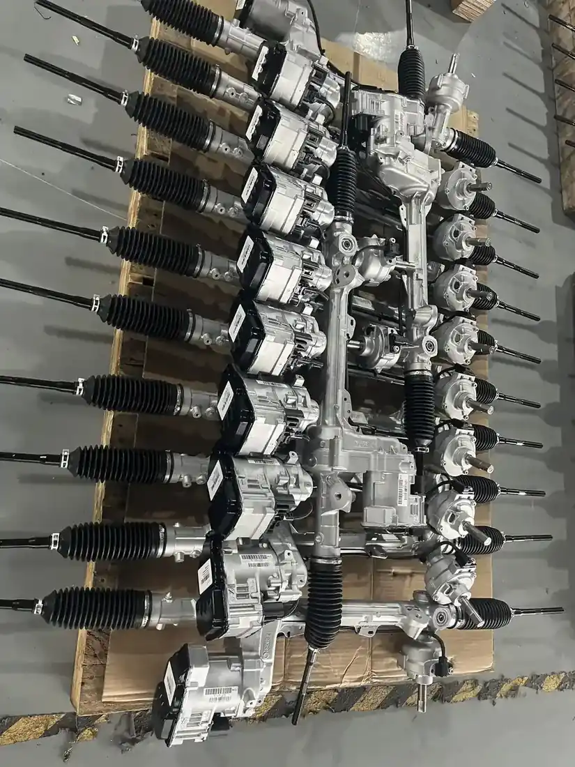 Close view of electric power steering racks laid out on a dark bench surface