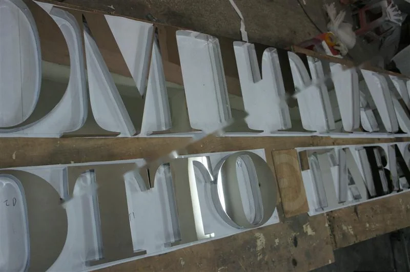 Metal sign letters on the workshop bench before finishing