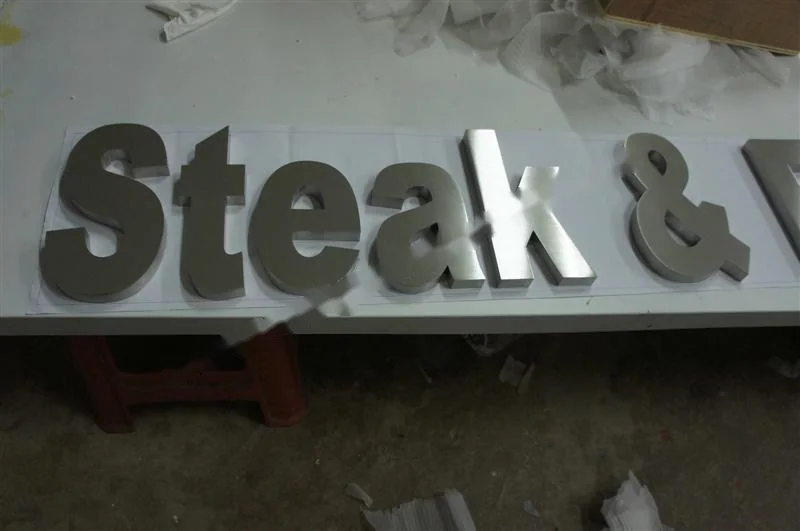 Metal sign letters on the workshop bench before finishing