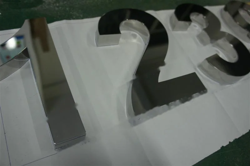Metal sign letters on the workshop bench before finishing