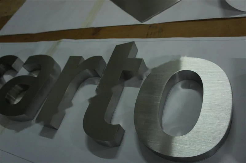 Metal sign letters on the workshop bench before finishing