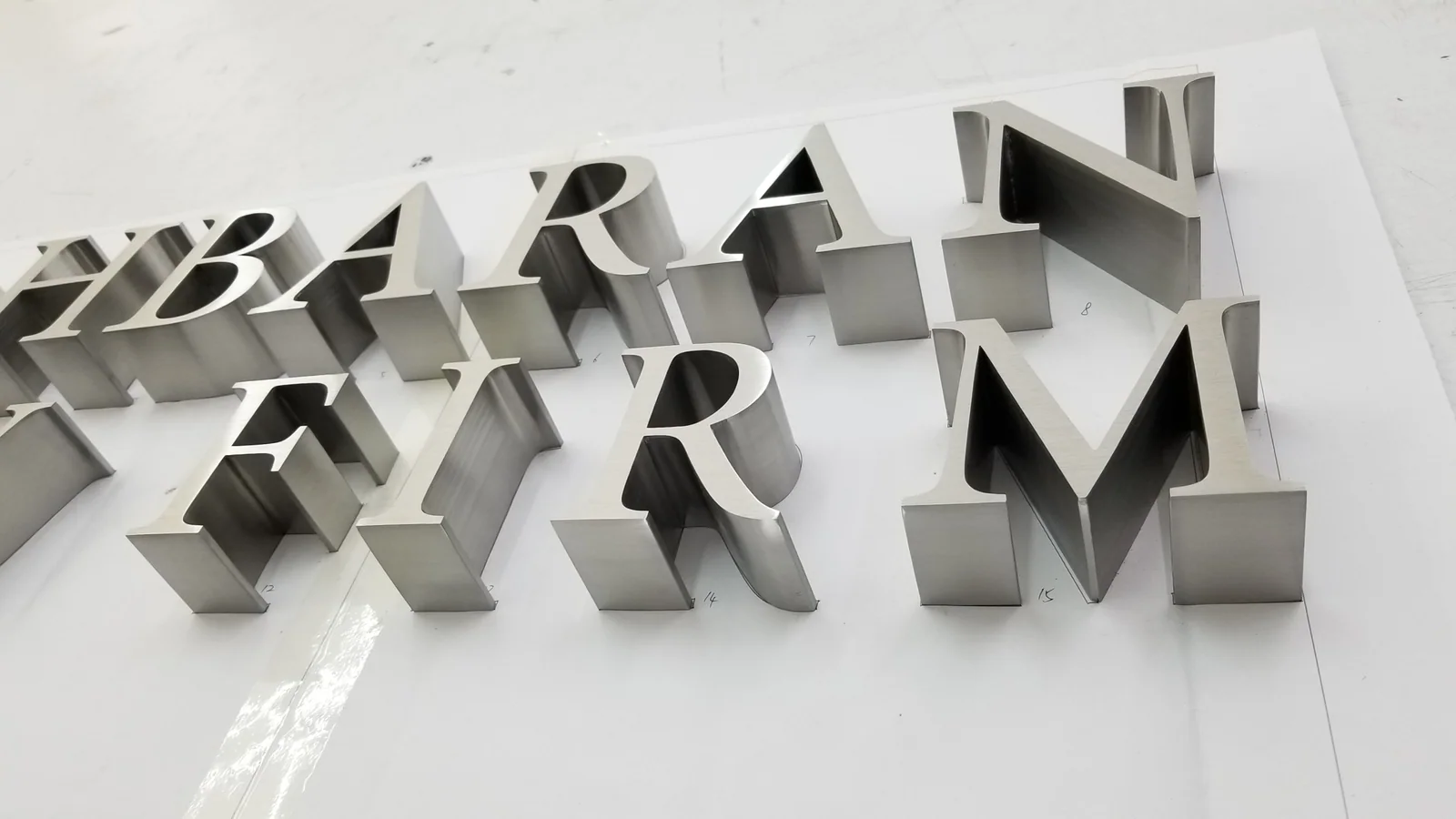 Brushed stainless steel relief letters installed across an exterior wall