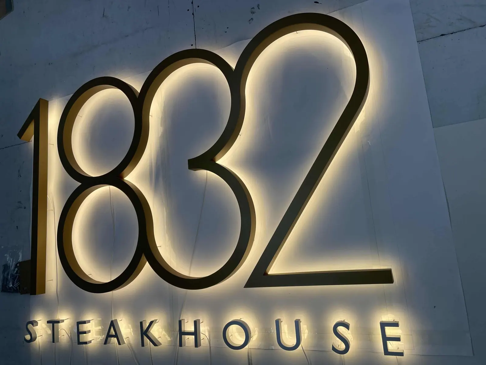 Halo-lit built-up letters in brass-finish metal mounted on a restaurant wall