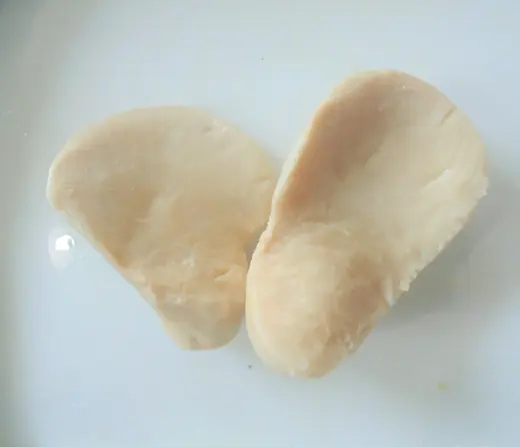 Two raw skinless chicken breast fillets on a white plate