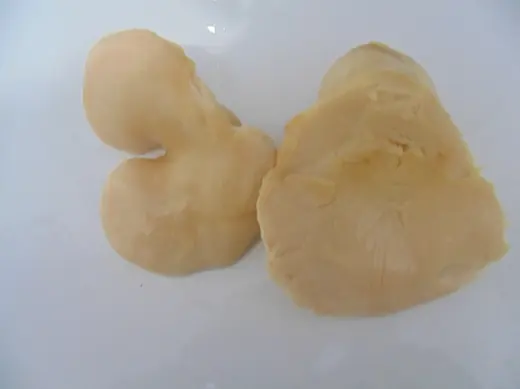 Two pale pieces of cooked chicken breast on a plain white surface
