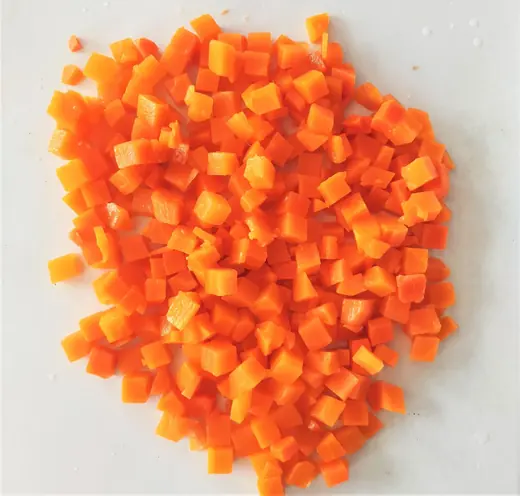 Pile of small diced orange carrot cubes on a plain white surface