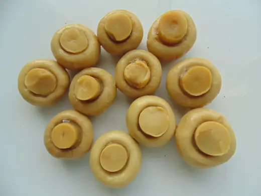 Marinated champignon mushrooms in an oval glass jar