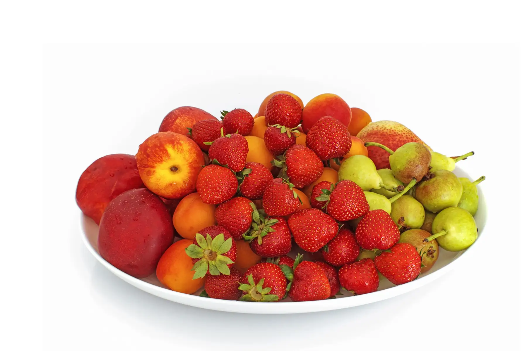 A white plate filled with fresh strawberries, nectarines, apricots, and green pears
