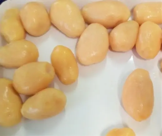 Peeled garlic cloves scattered across a white plate, close-up with soft uneven lighting