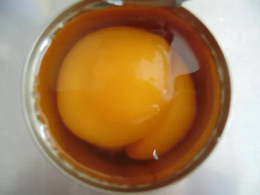 Open can of whole yellow peaches in amber syrup viewed from above on a plain surface