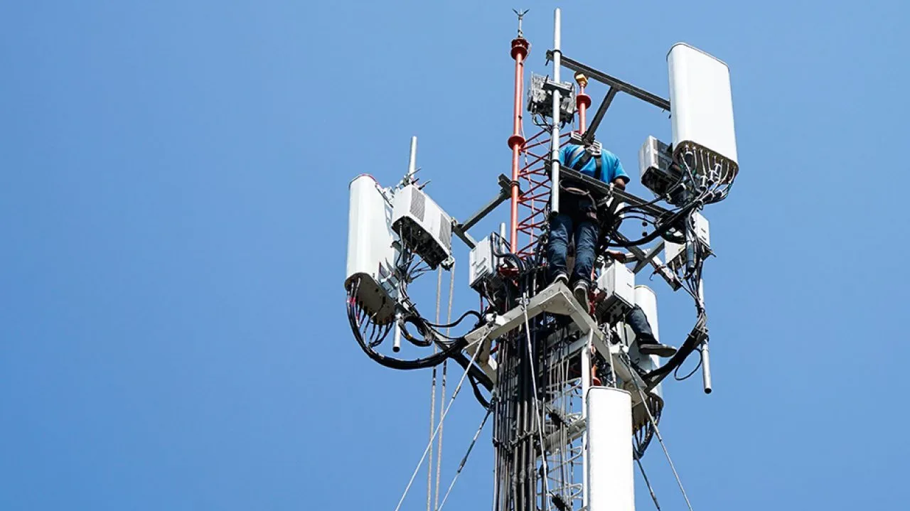 Engineer working on telecommunications equipment at height
