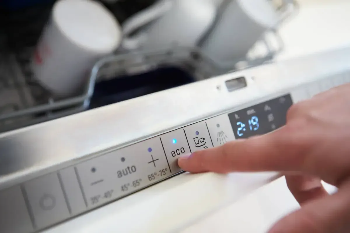 Hand operating the control panel of a consumer appliance