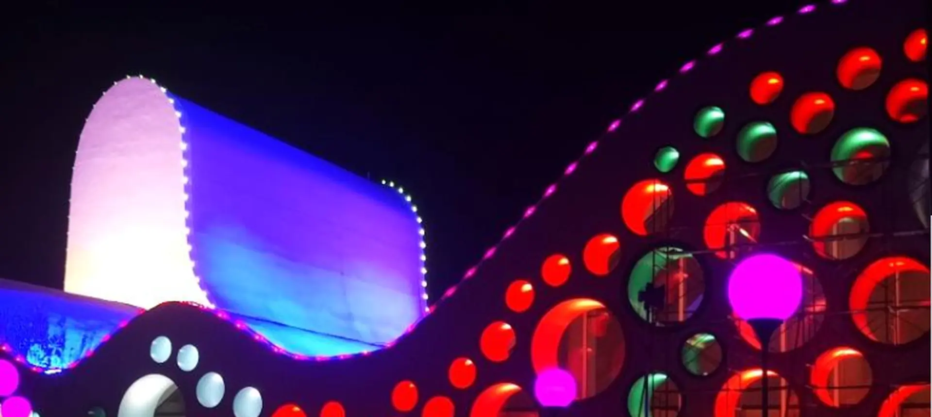 Curved art gallery facade covered with round full colour LED pixel points at night