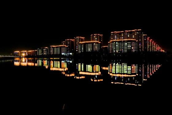 Waterfront building complex lit in warm white and reflected in still water