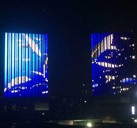Office towers with vertical blue linear light runs synchronised across both buildings