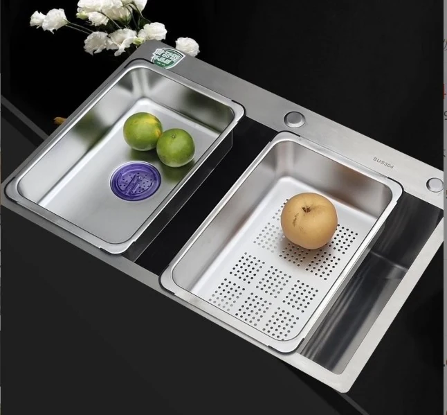 Dark worktop sink with two stainless baskets holding washed fruit