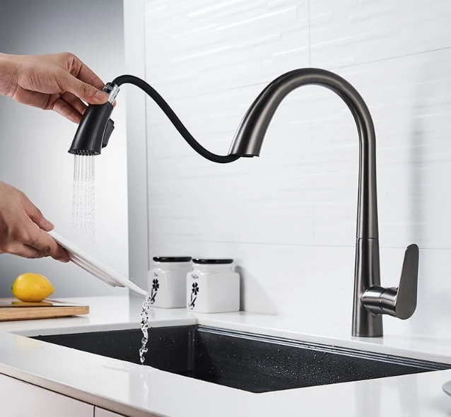 Hand rinsing a knife under a pull-down spray head at a kitchen sink