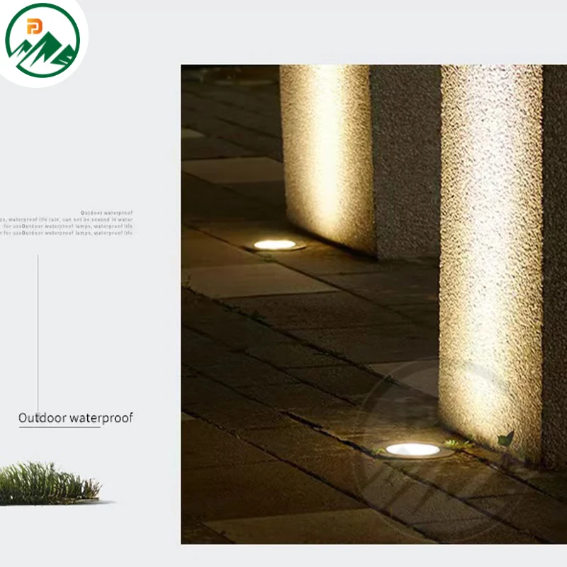 Underground light installed in a paved courtyard, illuminating a textured wall