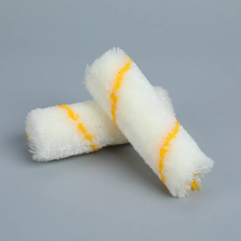 Two white paint roller covers with yellow stripes lying crossed on a plain gray background