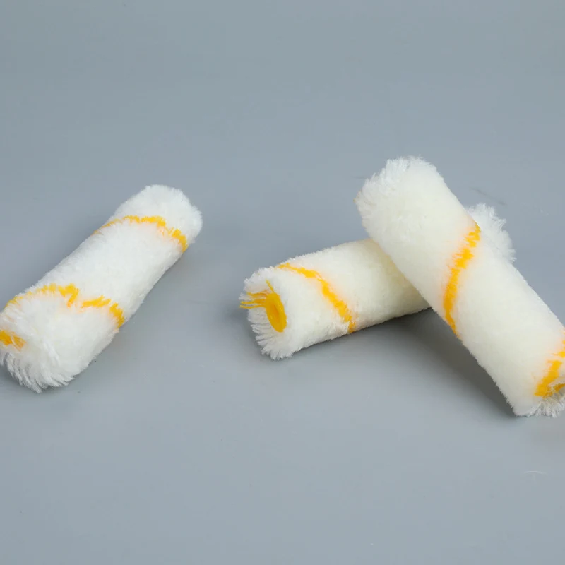 Three white paint roller refill covers with yellow stripes lying on a plain gray background