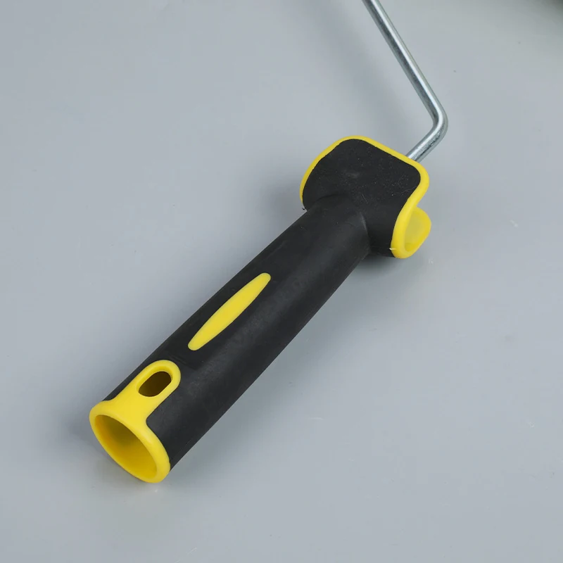 Paint roller frame with black rubber-grip handle and yellow accents on a plain light gray background
