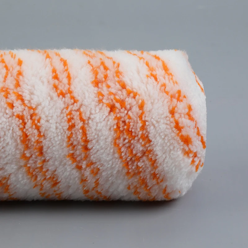 Close view of a white roller cover with orange diagonal stripes