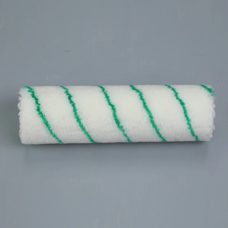 White paint roller cover with green diagonal stripes lying on a plain gray background