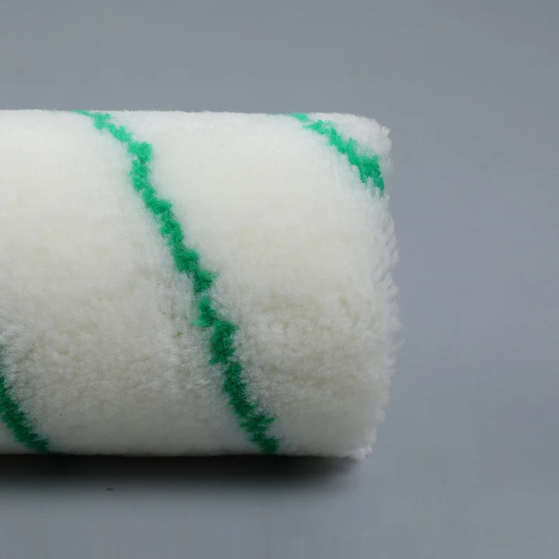 Close-up of a white paint roller cover with green glue stripes on a plain gray background