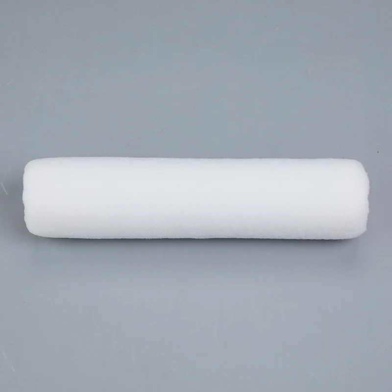 White fabric paint roller cover lying on a plain grey background