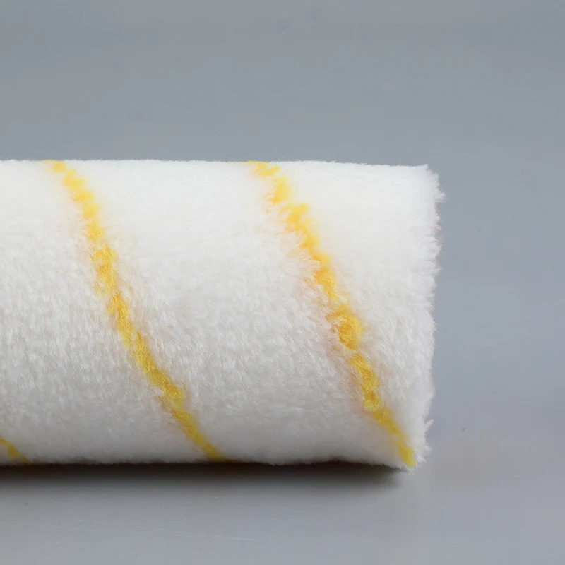 Close view of a white roller cover with yellow diagonal stripes