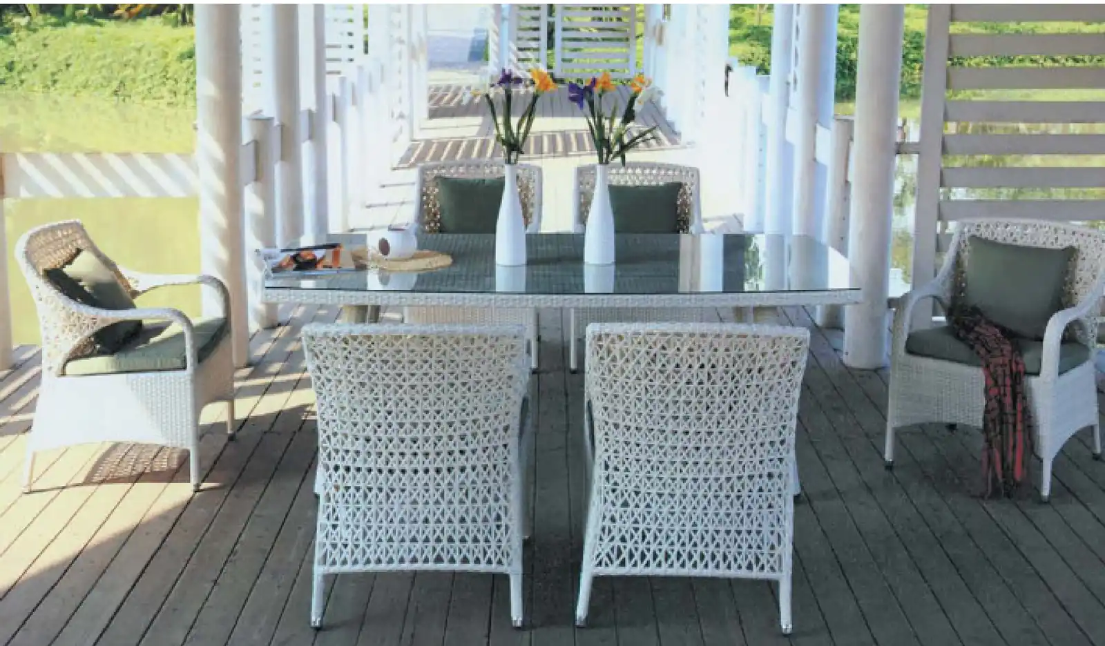 White synthetic rattan dining set with four armchairs and a table on a timber deck