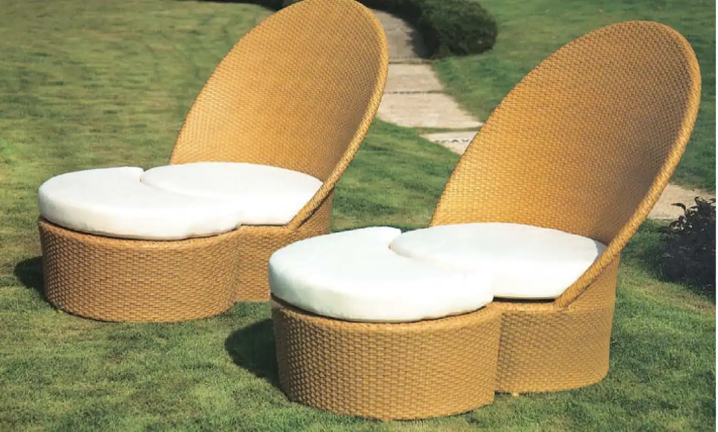 Pair of tan rattan sun loungers with cushions on a lawn