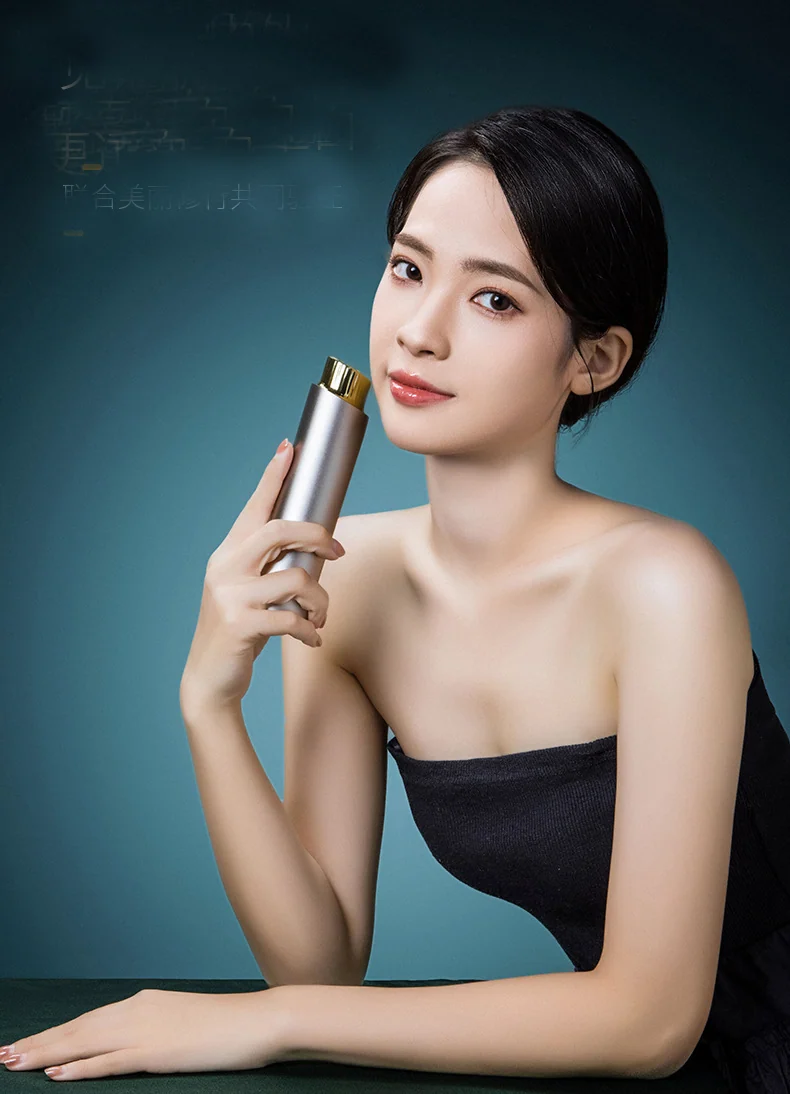 Gold finished radio frequency beauty device held against a dark background