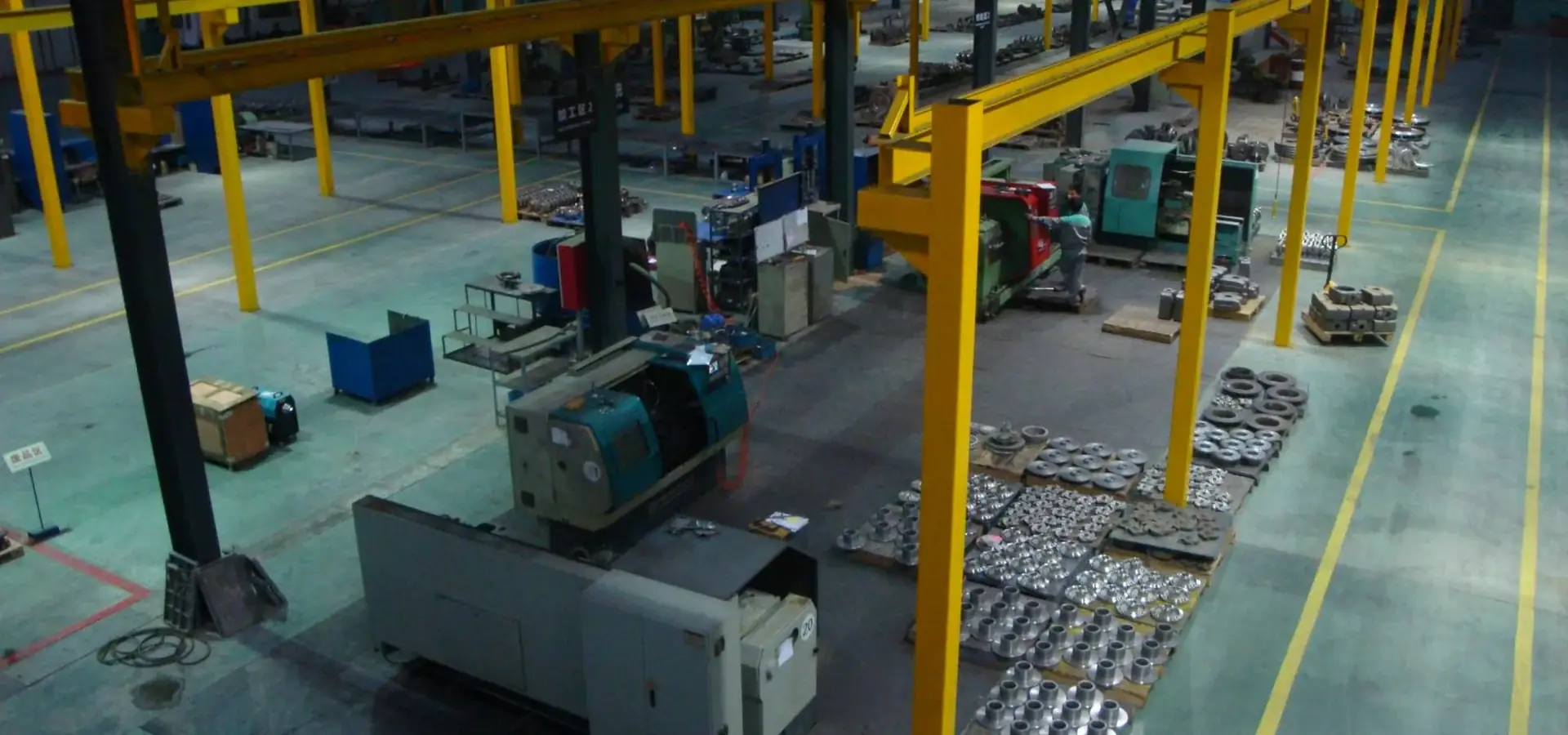 Machining bay with overhead gantry cranes and machined castings laid out on the floor