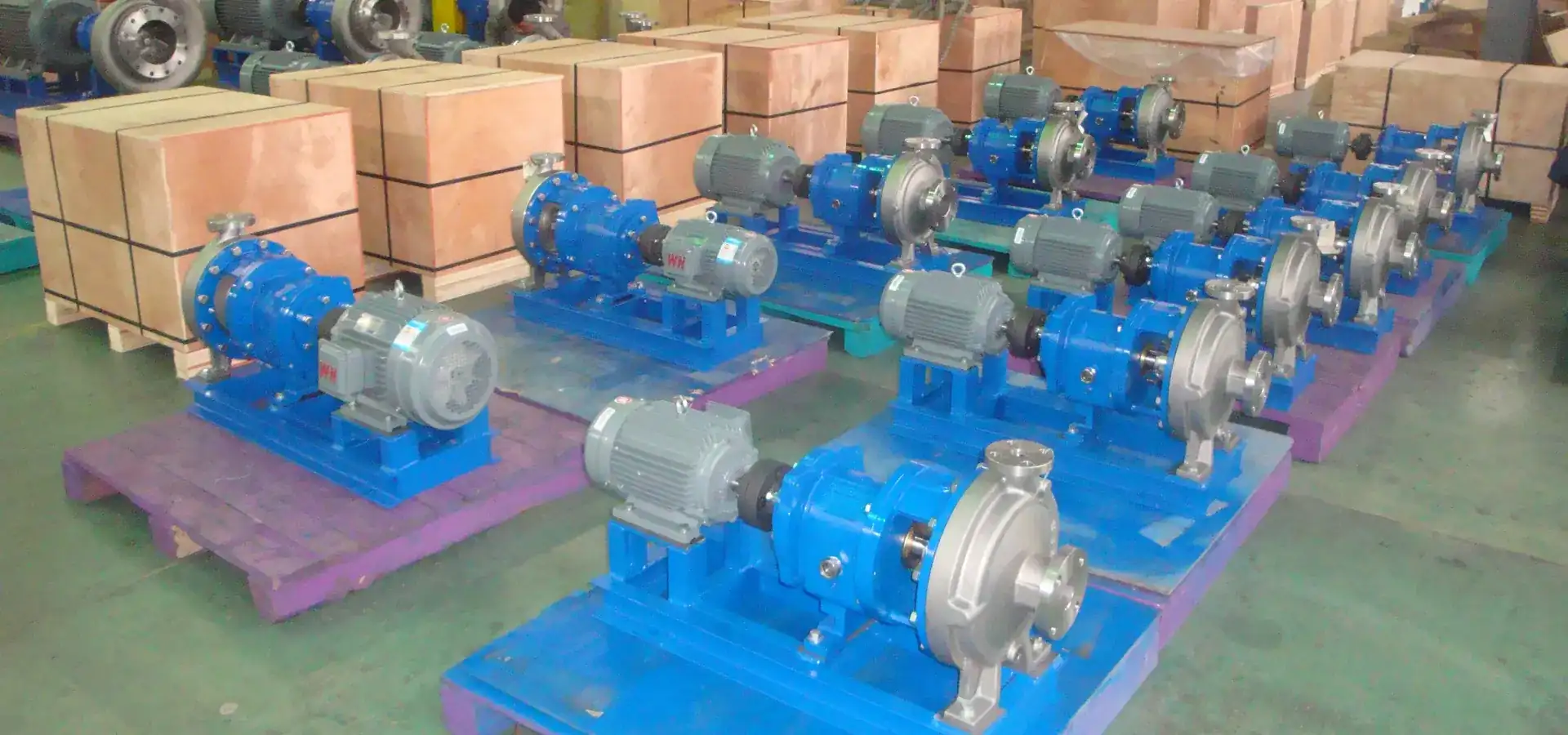 Rows of assembled centrifugal pump sets staged on pallets next to export crates