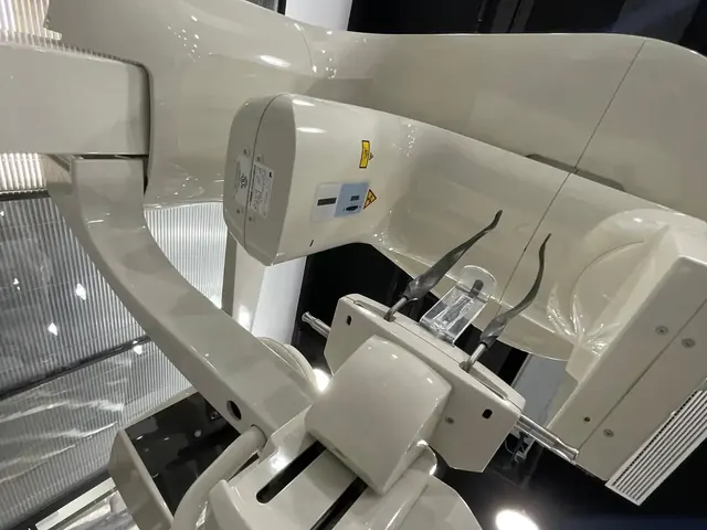 Carestream CS 9300 Select close-up of the rotating C-arm showing the X-ray tube housing with X-ray hazard label, the flat-panel detector assembly, patient positioner with carbon-fibre bite block stand and temple-stabilizer arms