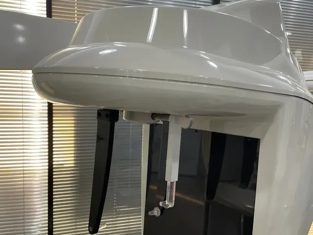 Close-up of the Carestream CS 9300 Select TFT flat-panel detector module showing the carbon-fibre imaging window, bite block support pillar, and the paired black carbon-fibre temple-stabilizer arms that keep the patient's head immobilized during acquisition