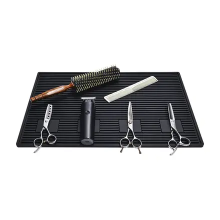 Black PVC barbershop station pad holding clippers scissors and a brush